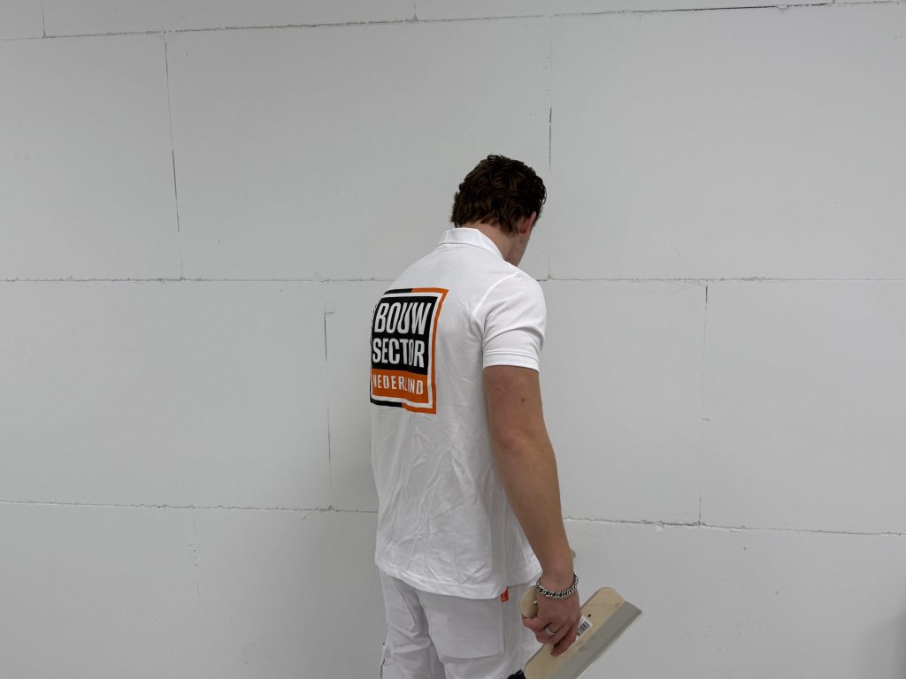 Stukadoor van Bouwsector Nederland met een plakspaan in de hand voor een kale wand van gipsblokken